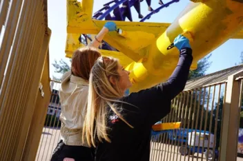 A couple of women painting a yellow object
AI-generated content may be incorrect.